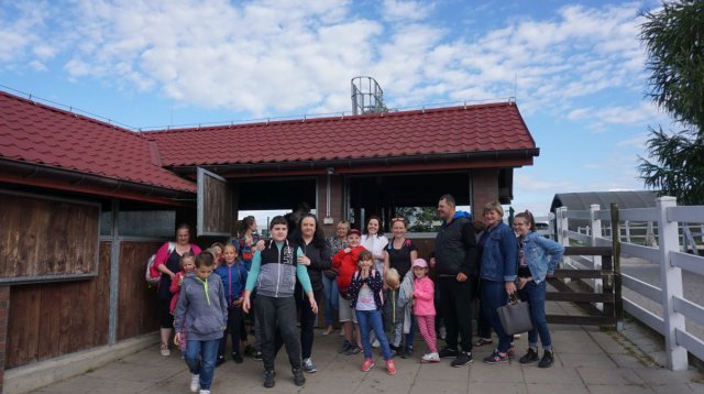 Na zdjęciu znajduję się cała grupa uczestników wycieczki, która stoi przy stajni 
w której znajdują się lamy.
